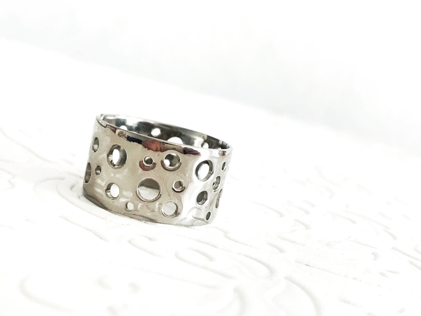 Pure titanium boho-style statement ring with varying hole sizes and a slightly adjustable design. Lightweight, durable, hypoallergenic, and tarnish-resistant